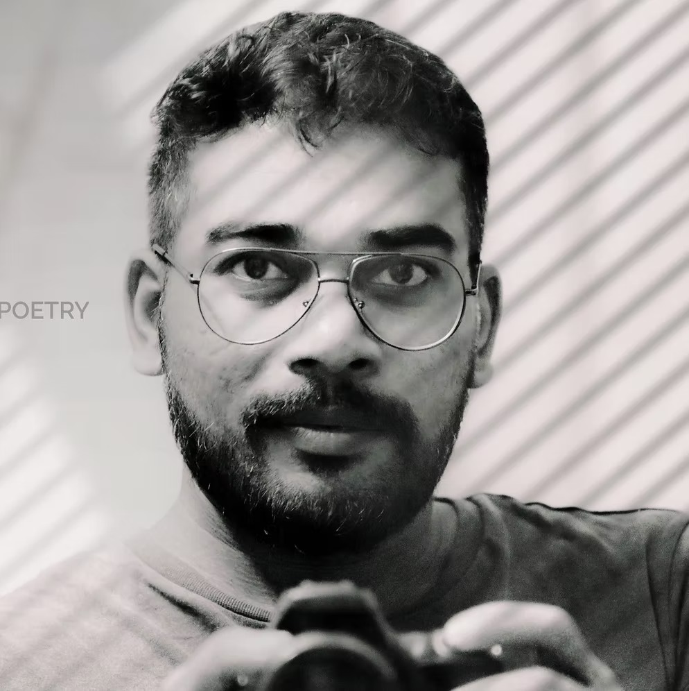 Anoop Vijayan, in black and white, holding a camera